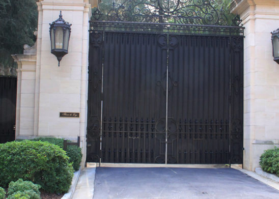 wrought iron and sheet metal bifold auto gate and hinged pedestrian gate