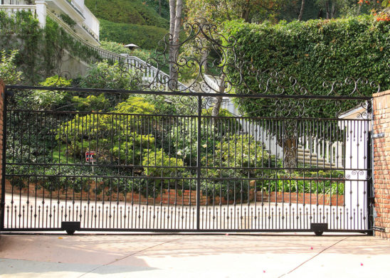 wrought iron sliding auto gate with vertical spindles and scrolled top