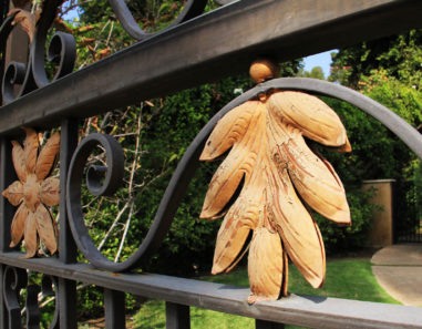 side close up of wrought iron gate accented with tropical gold flowers and leaves